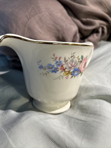 White ceramic pitcher with gold rim, floral print in pink, blue, and yellow, labeled “Made in U.S.A.”