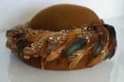 Brown hat with 100% wool EXCELLO, featuring colorful pheasant and quail feathers with patterned brown, black, and white plumage.