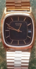 Sharp gold quartz analog wristwatch cushion shaped case and black dial