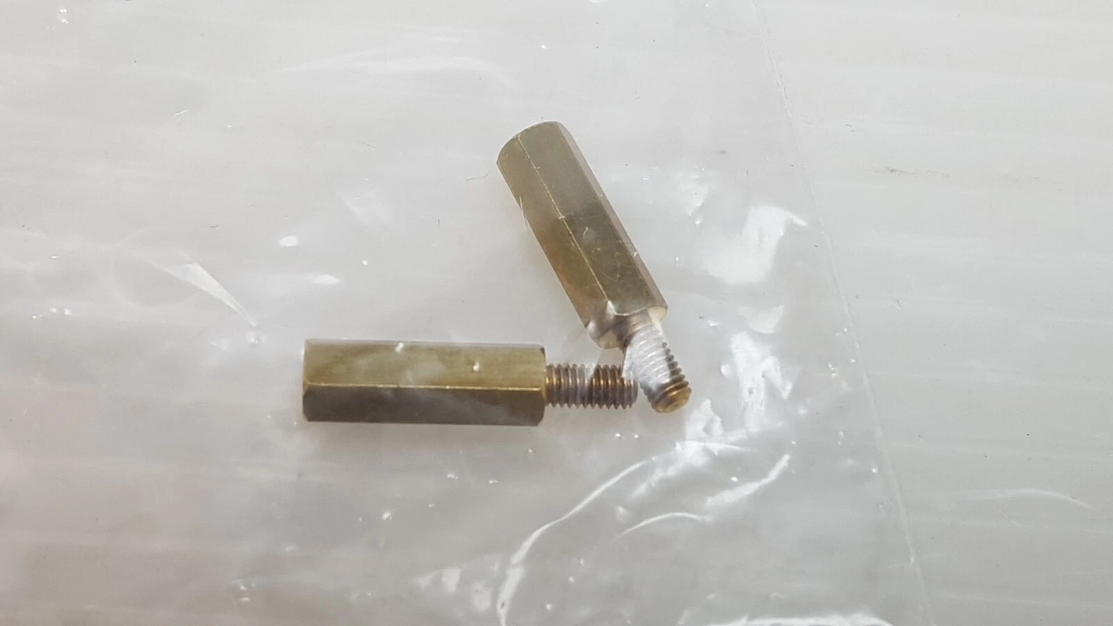 Two brass hex standoffs in a bag