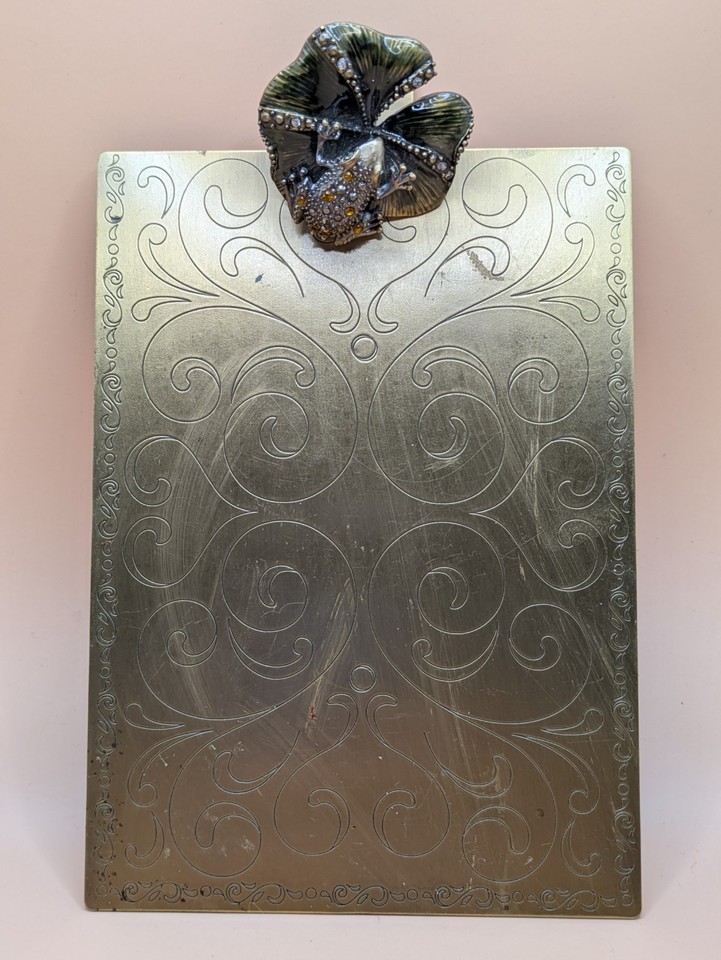 A brass clipboard doubled as a jeweled frog-on-a-lily-pad photo holder is one of the most delightfully bizarre desk pieces imaginable — pure vintage whimsy.