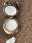 Two round gold Liberty Bell trinket boxes with white circular lids, hinged together by twisted gold rope detail.