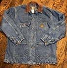 Blue denim Carhartt C59DST chore coat with brown collar, front button closure, and small yellow Carhartt logo patch.