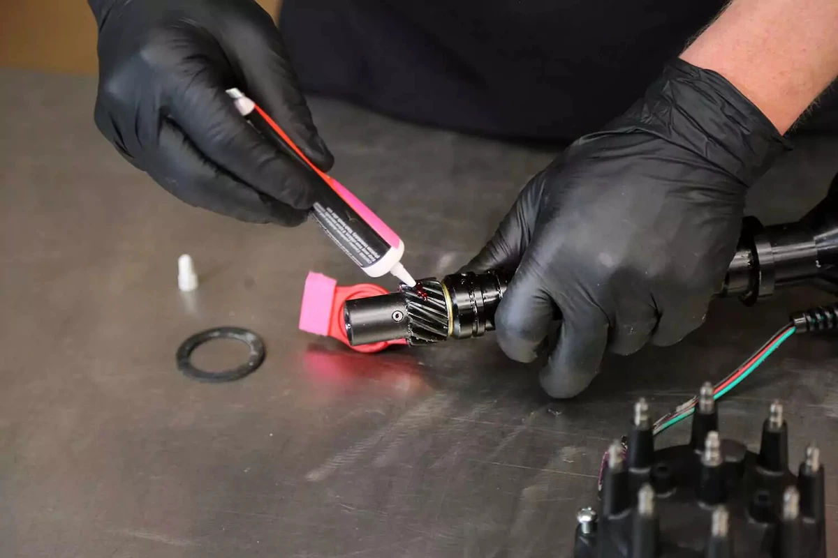 A mechanic applies assembly lube to the distributor gear.
