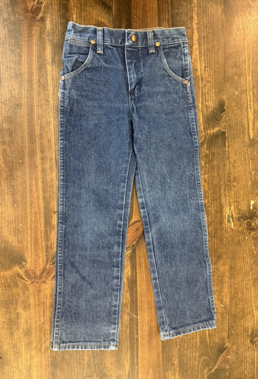 Blue denim kids’ Wrangler jeans, size 7, with front pockets, brown leather patch on waistband, made in USA.