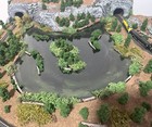 Z scale model layout with pond, rocky cliffs, tunnel, and yellow and black train on tracks.