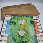 Vintage 1961 Stratego board with green-bordered game board, box, and instructions in red folder on wood surface.