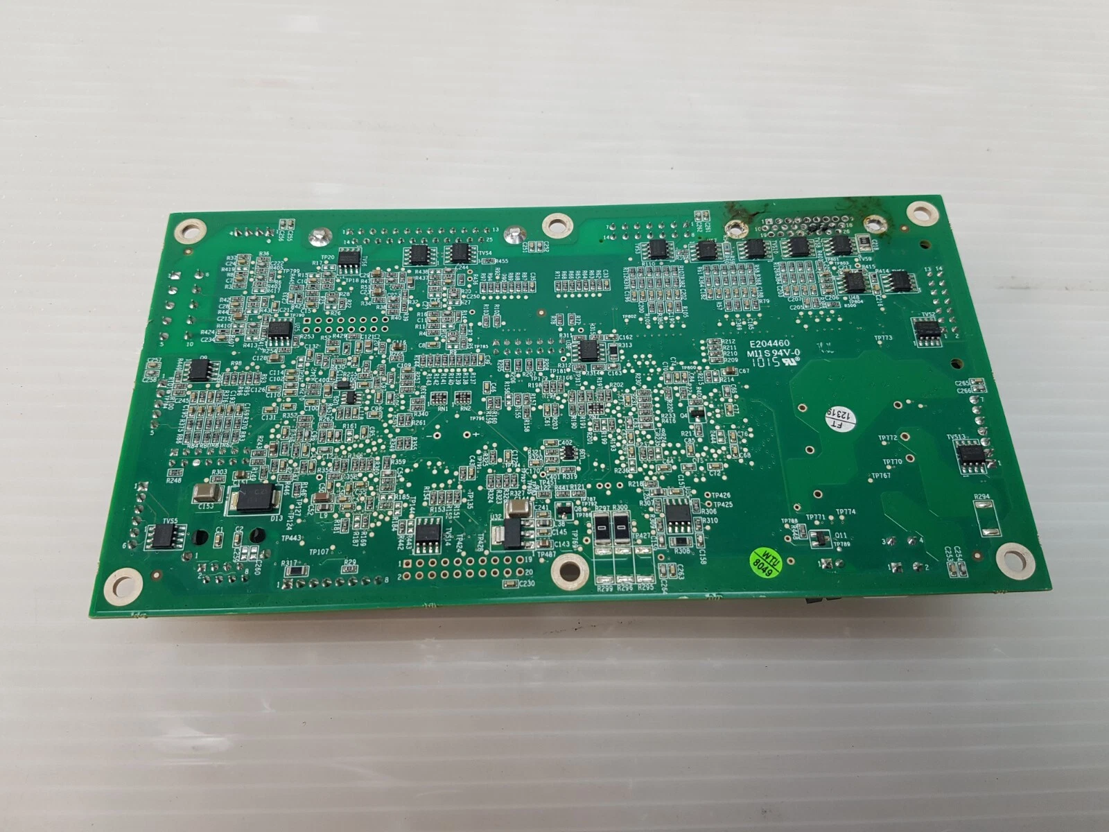 Solder side of the Lumenis MMCU board at an angle, showing marks near the removed connector