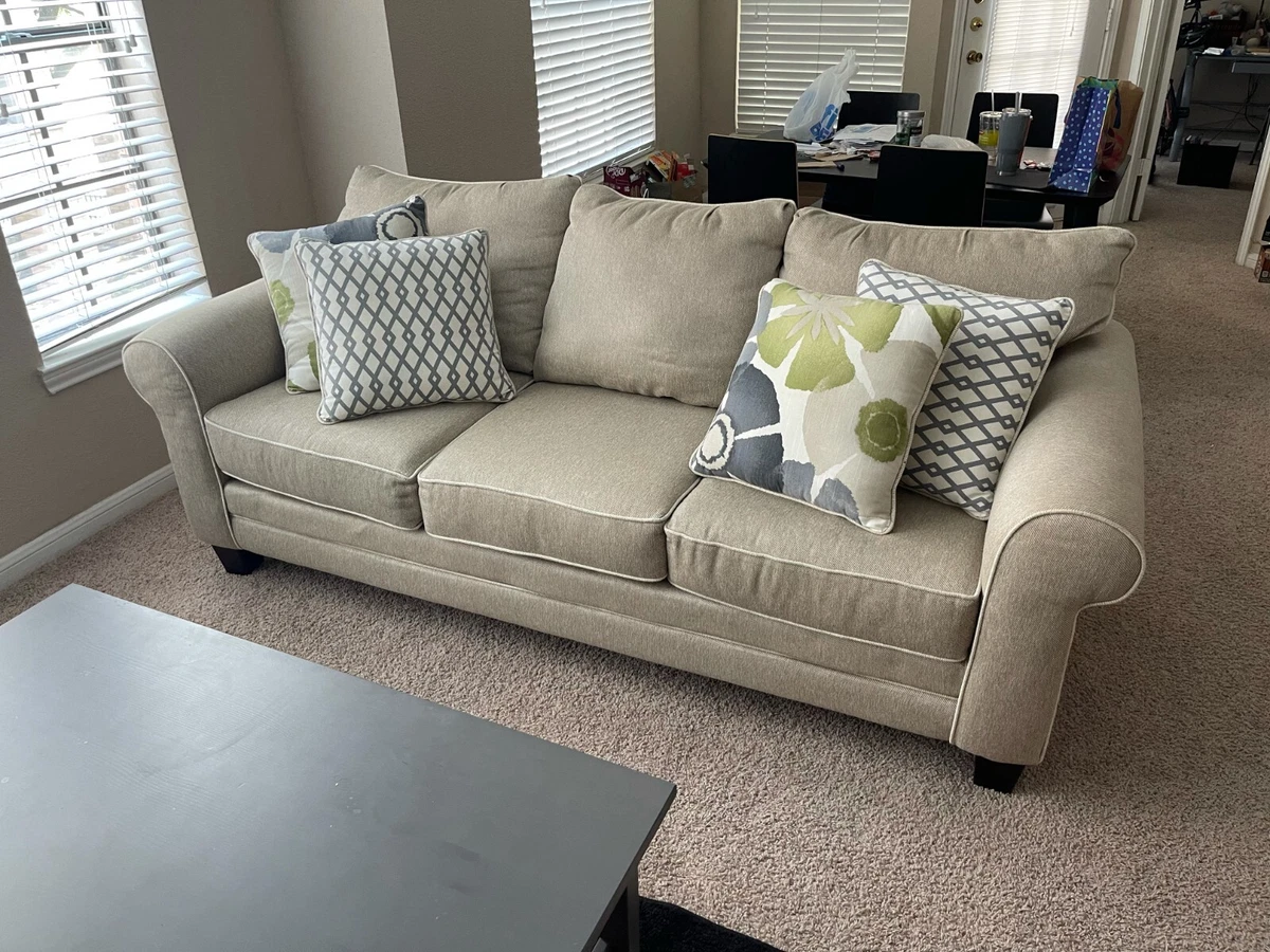 Beige 3 seater sectional couch with green and gray accent pillows