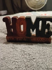 wooden decorative sign with the word "HOME" carved in block letters, and "SWEET