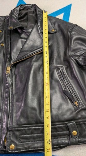 Black vintage leather Langlitz motorcycle jacket size 46 with front zipper, snap buttons, and yellow measuring tape.