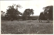 Two Men in Suits Seated in Flower Field Postcard RPPC 1910s Wooden Bridge Rural