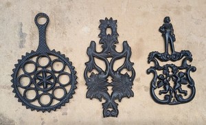 3 Vintage Black Cast Iron Trivets Hex T-9, Laughing Moons, Cupid & Sailor