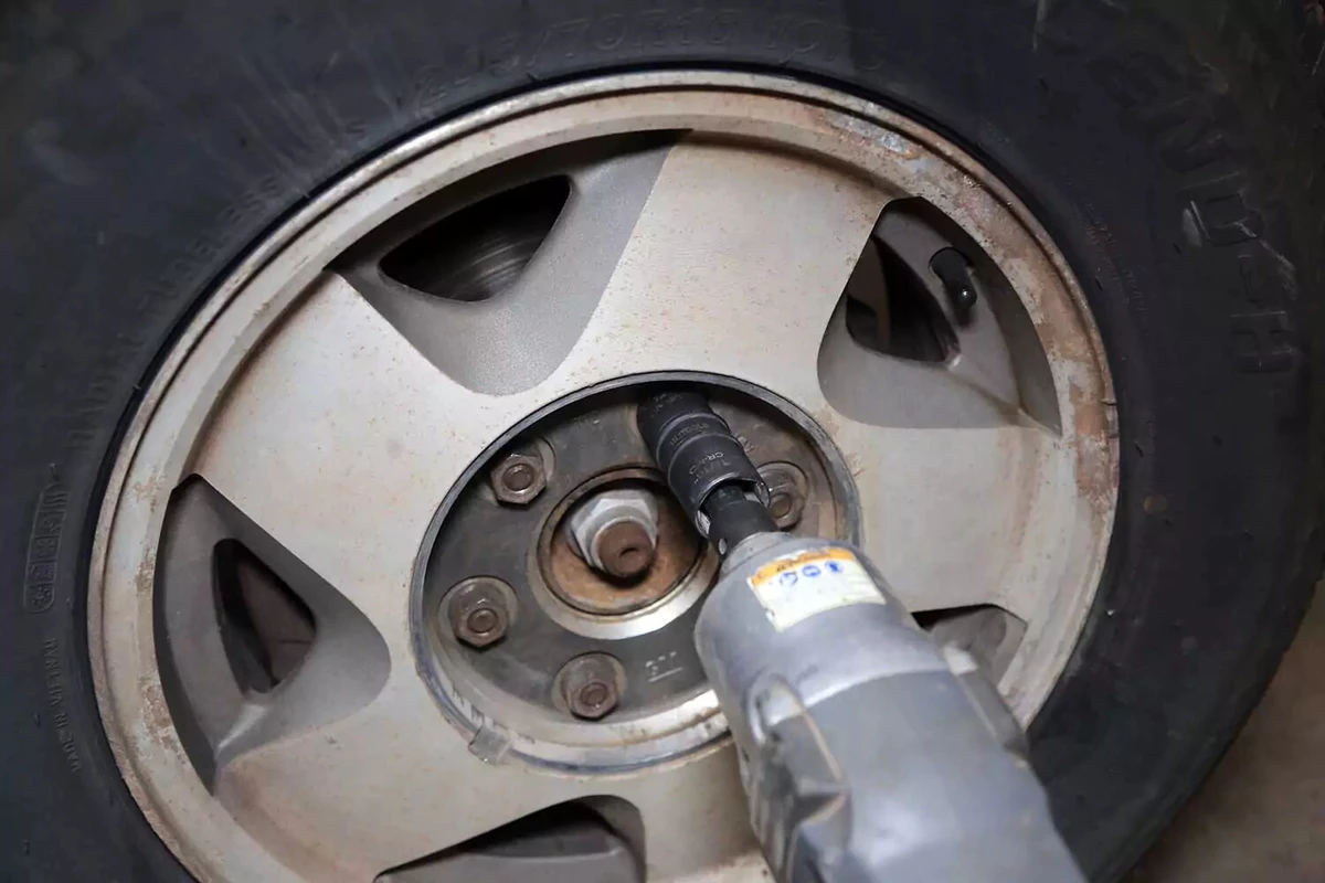 A mechanic removes a lug nut with an impact wrench.