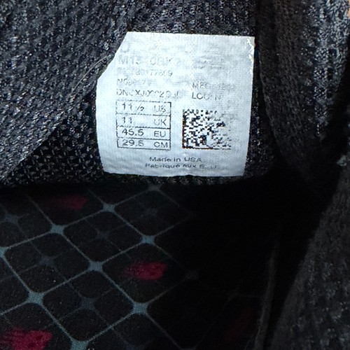 White New Balance 1540V2 tag with gray text, barcode, and size 11.5 D black shoe label made in USA.