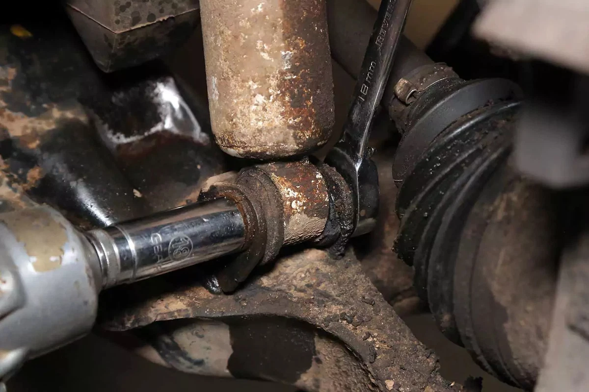 Removing the nut from the lower shock mount bolt with a socket and box wrench.