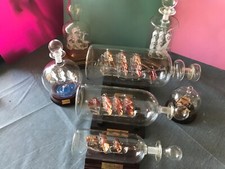 Collection of 7 glass ships in bottles with stands