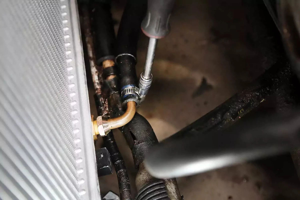 Tightening the transmission cooler hose clamp with a socket driver.