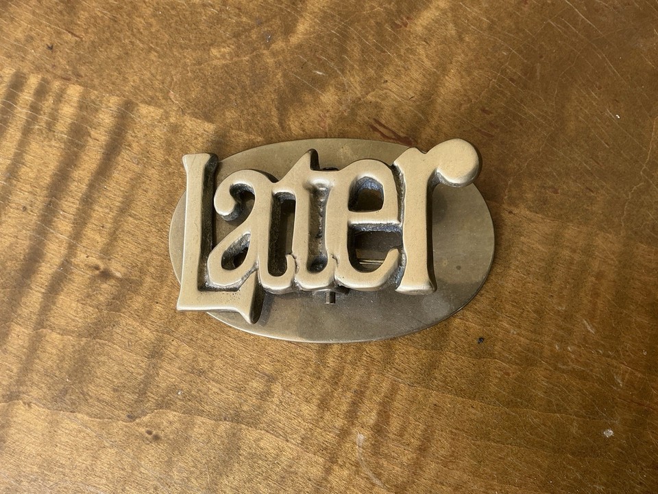 A solid brass paperweight clip that literally says "LATER" — brutally honest passive-aggressive desk energy, and it's beautifully made.