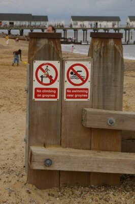 Photo 6x4 Amusing signs at the Southwold Groynes The pier is visible in ...
