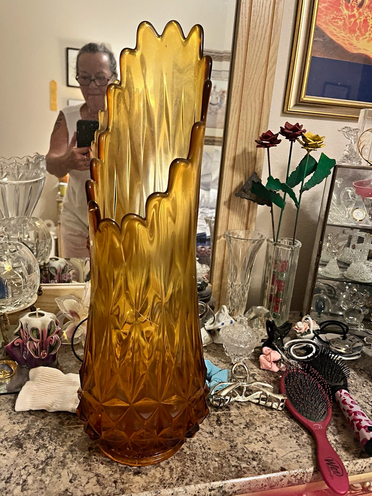 Tall amber glass vase with a scalloped rim on a white background.