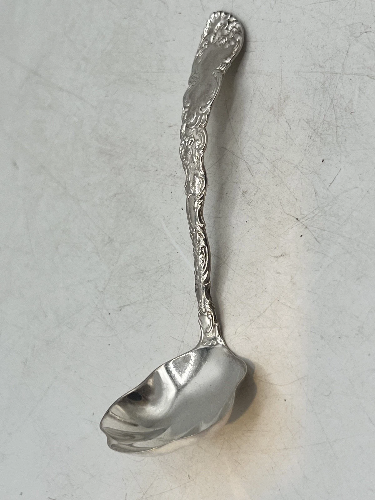 Ornate sterling silver sauce ladle with floral handle