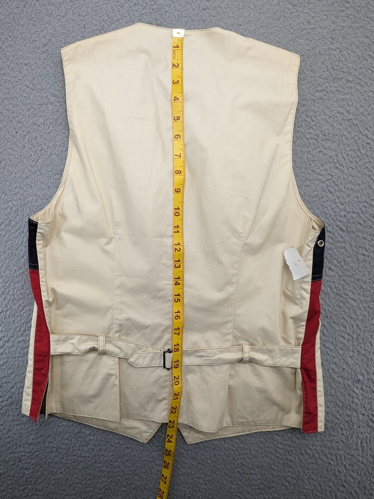 Back zipper of Faconnable vest, medium navy, with red and white diagonal stripes, yellow measuring tape.