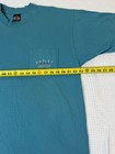 Teal Harley-Davidson men’s XL T-shirt with front pocket, yellow measuring tape, and white “Harley-Davidson Made in USA” text.