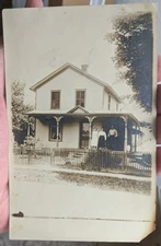Real Photo Postcard Family on the porch of house with picket fence early 1900s