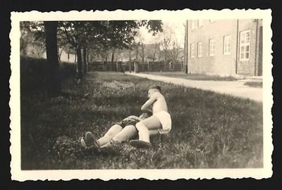 Photograph Two people in swimming trunks lying on a meadow resting 