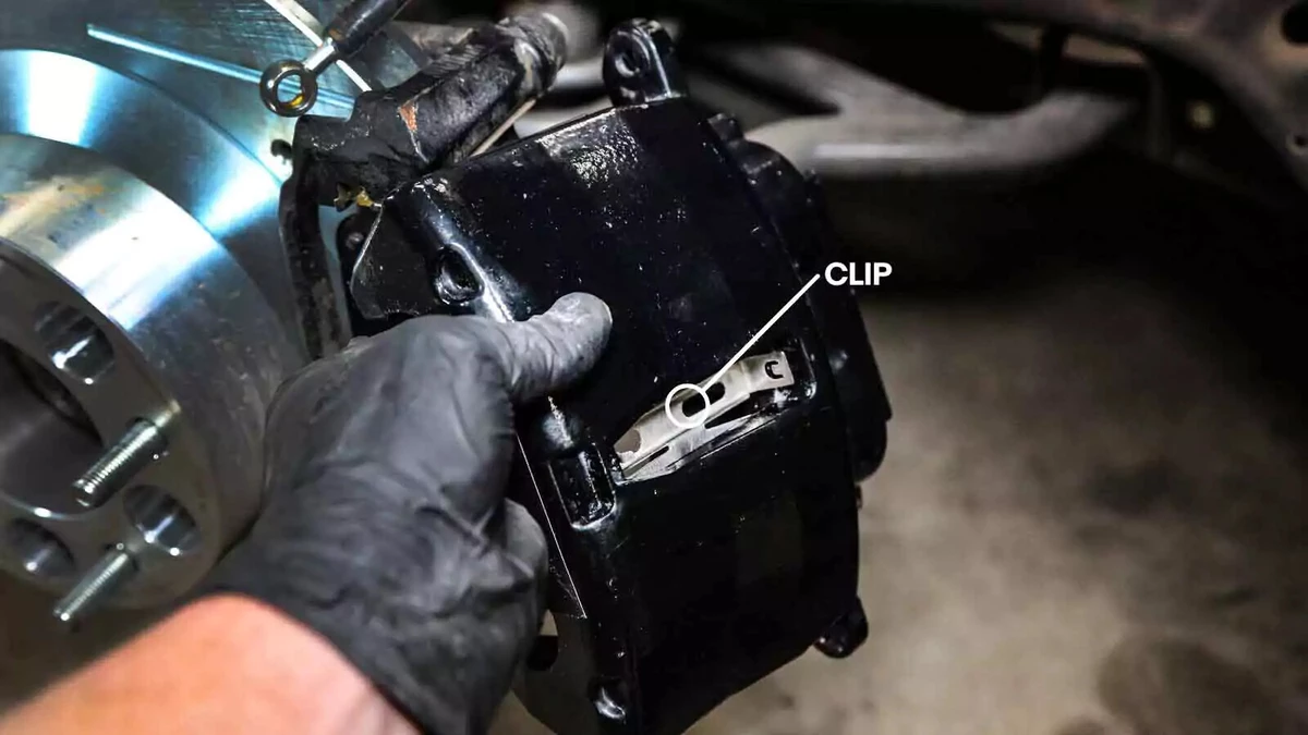 A mechanic replacing the brake caliper clip.