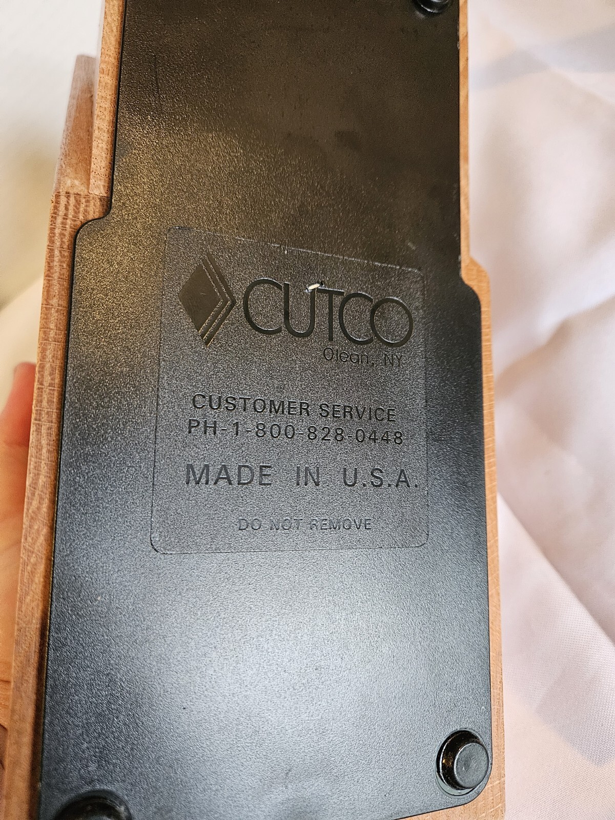 Brown woodgrain base of CUTCO Solid Honey Oak knife storage block with black text reading “Customer Service” and “Made in U.S.A.”