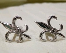 pair of silver-tone cufflinks with a fleur-de-lis design.