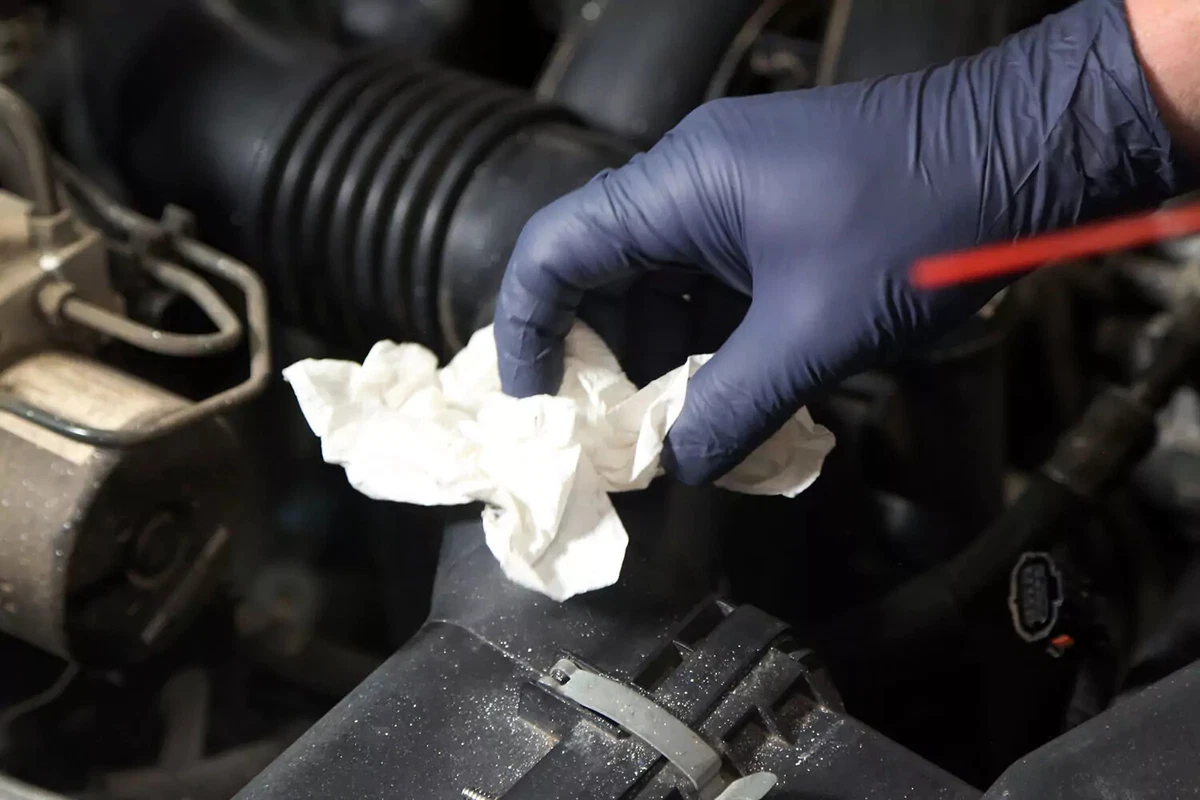 Using a towel to clean an air intake tube.