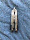 Gerber MP600 USA Made Multitool 0870314S3 with silver blade and black accents on a blue fabric background.