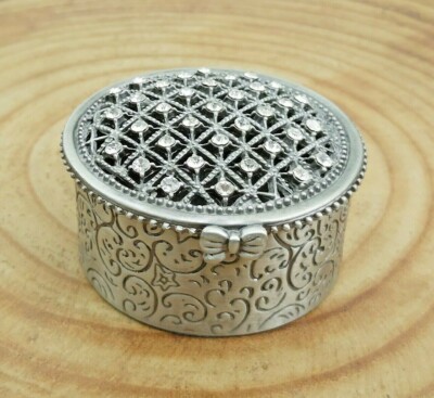 Runde silberfarbene Schmuckschatulle mit Deckel aus Metallprägung und Strass. schwarzes Futter