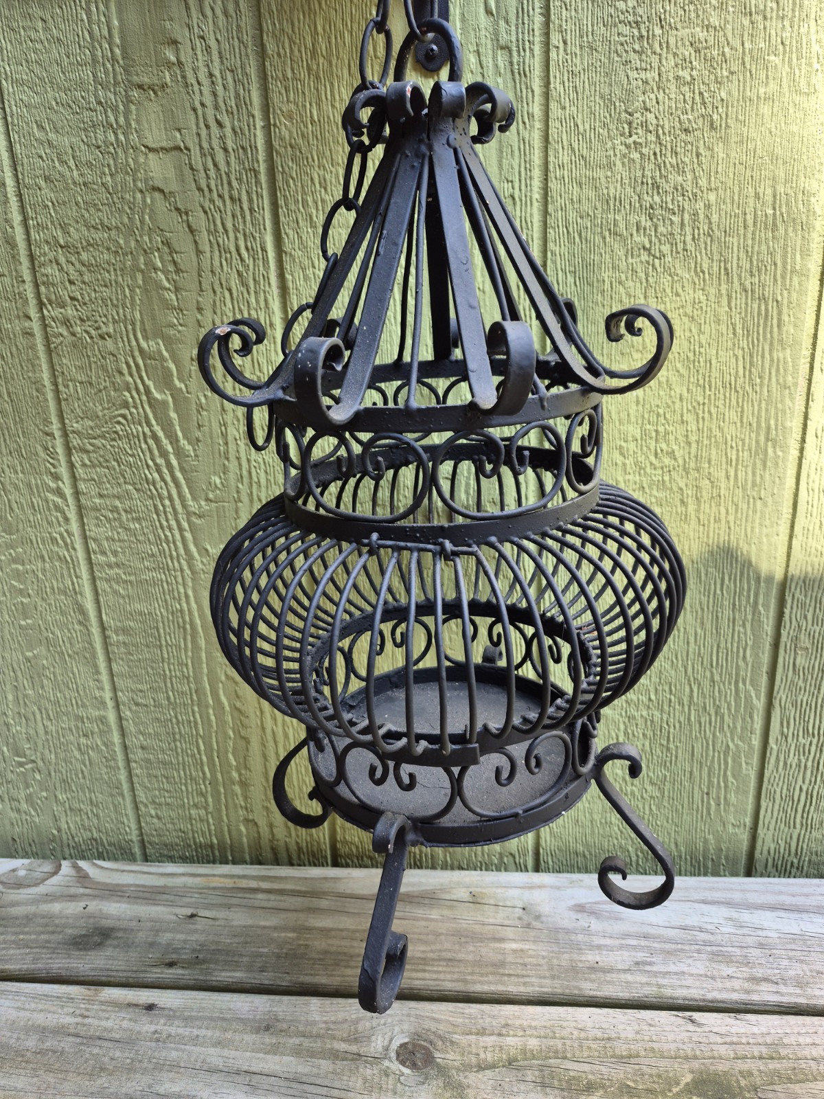 Antique ornate wrought iron birdcage with scrollwork, shown empty without a bird
