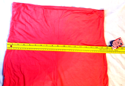 Folded bright pink Style Plus size 2X yoga pants with white drawstring, lying on a measuring tape with yellow vertical scale.