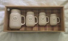 This set of four white ceramic mason jar measuring cups features embossed text.