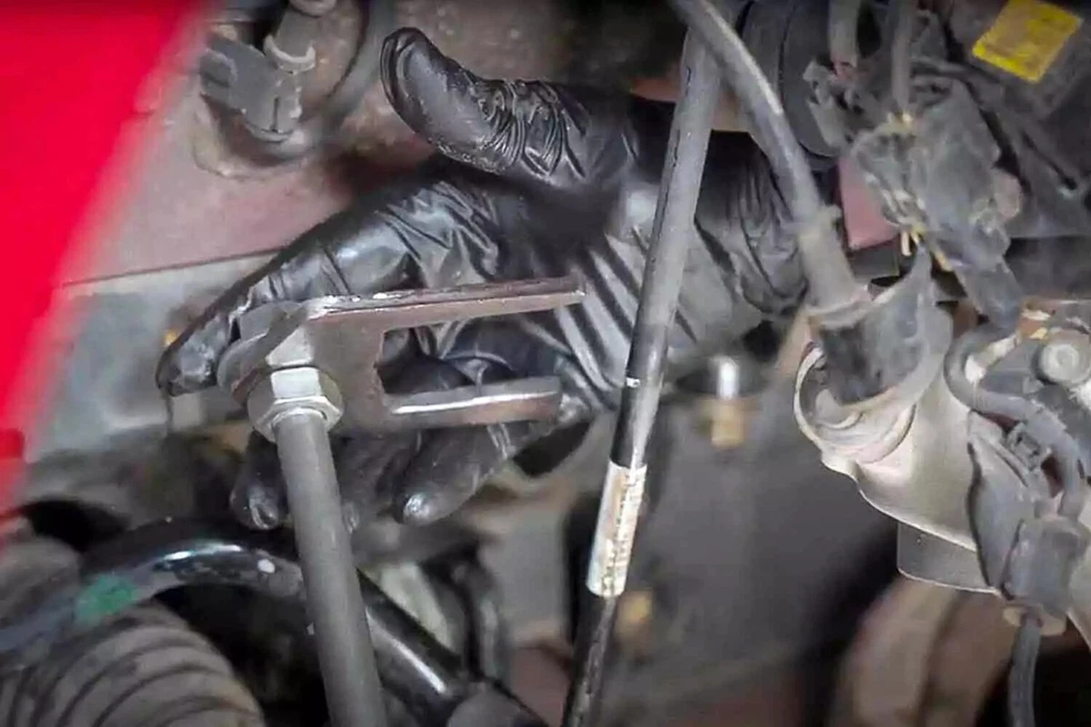 A mechanic wearing a black nitrile glove uses an axle puller.