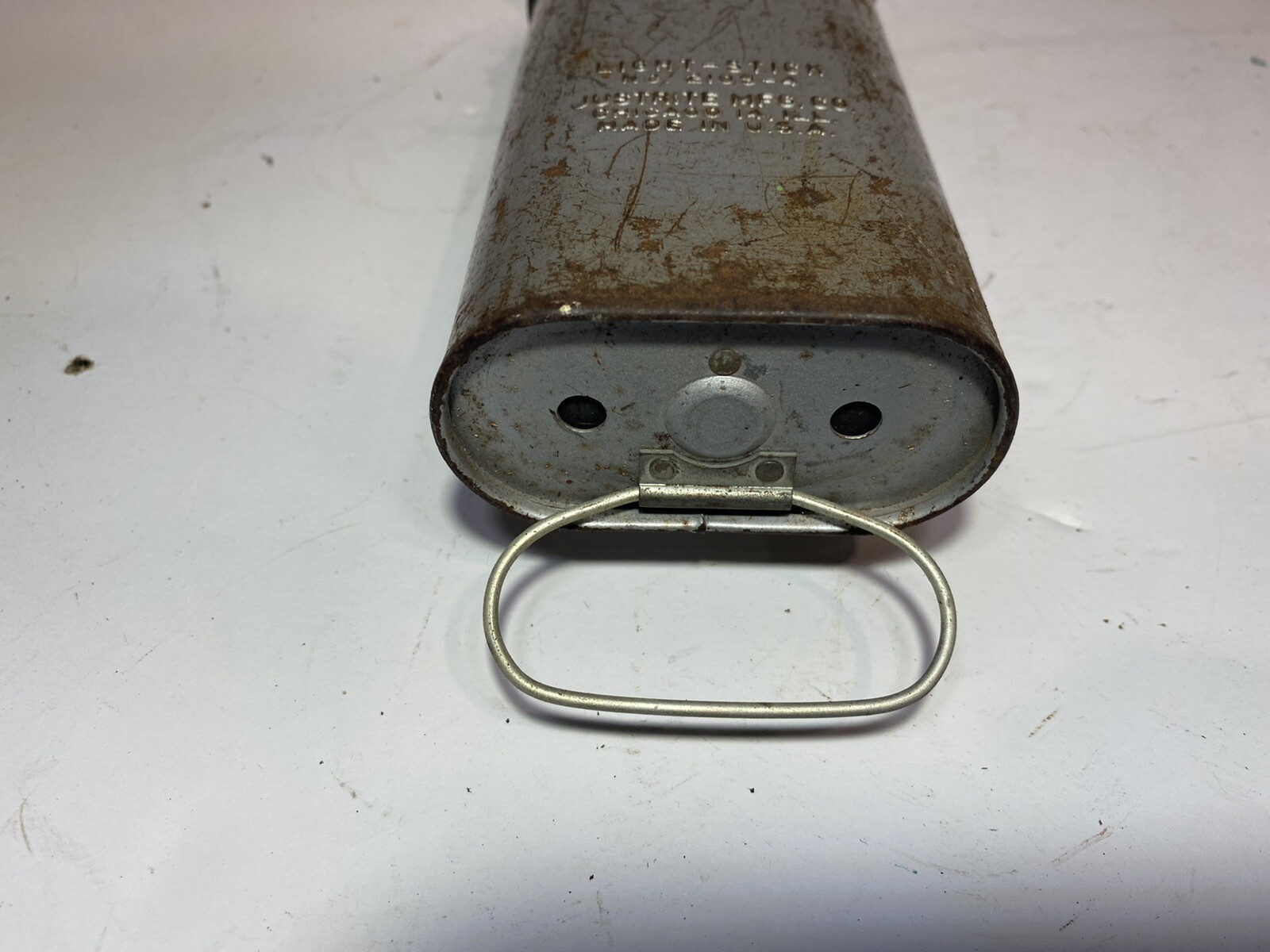 Close-up of worn silver metal flashlight bell with black text and circular base on a white background.