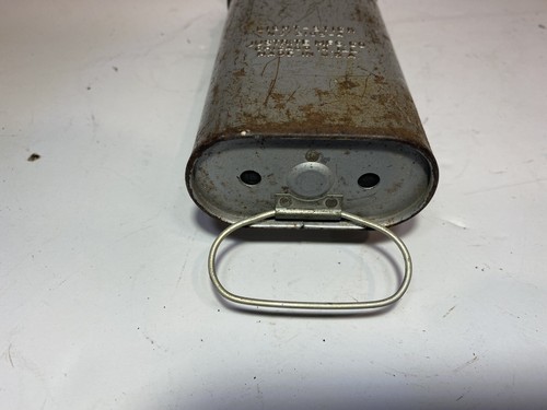Close-up of worn silver metal flashlight bell with black text and circular base on a white background.