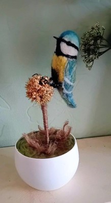 Nadelgefilzte Blaumeise thront auf Blütenkopf. Handarbeit.