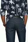 Man wearing navy blue denim bootcut jeans with white palm tree print, back pocket stitching, and gold-trimmed waistband.