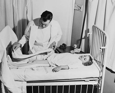 Doctor removes special casts to examine weakened legs of a polio p- Old Photo