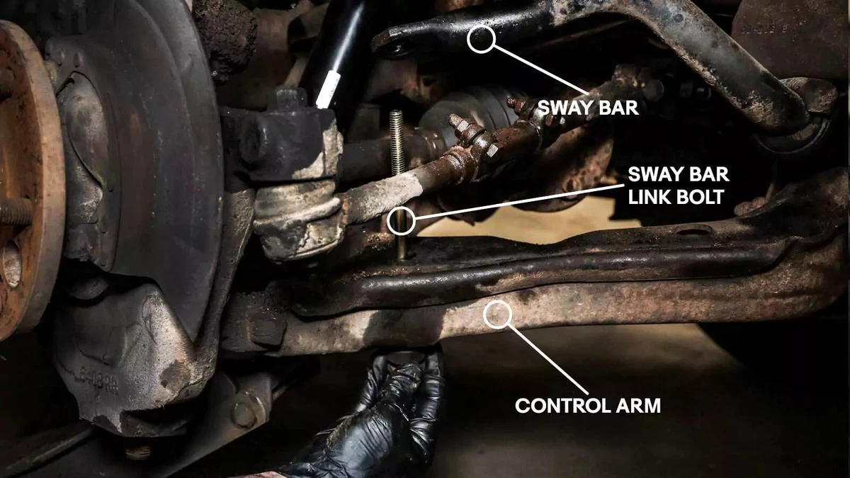 A mechanic threads the end link assembly through the bottom of the lower control arm.
