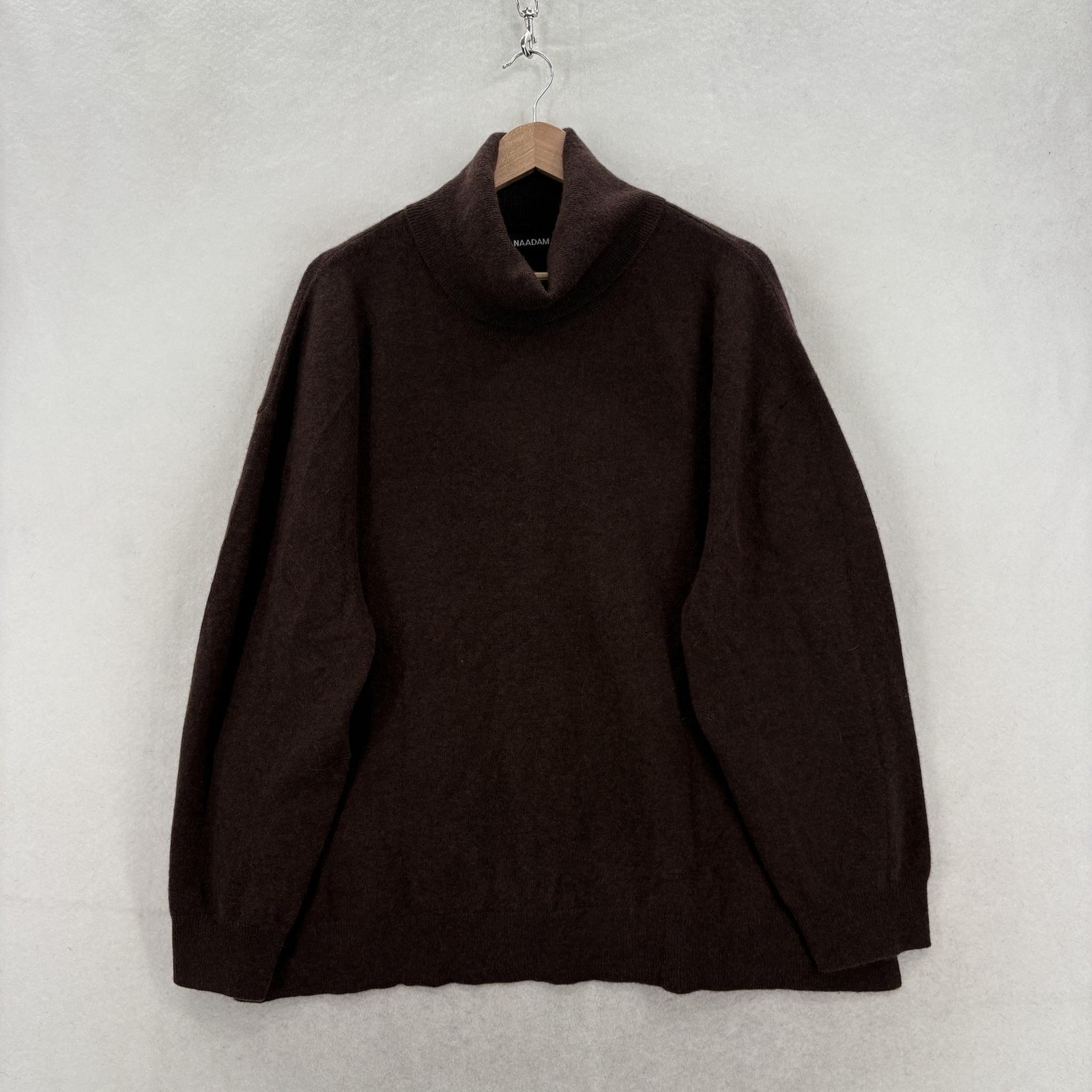 Brown cashmere turtleneck sweater on a hanger.