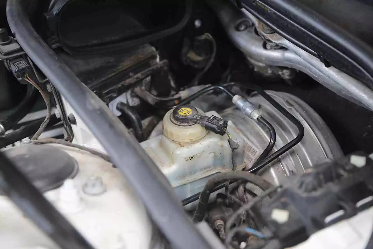 The brake fluid reservoir located next to the brake master cylinder of a vehicle.