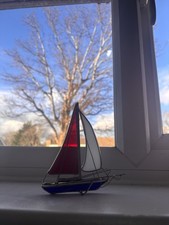 vintage stained glass sailboat ornament with a red and white sail and blue hull