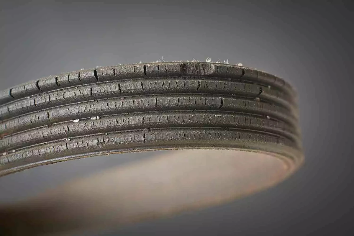 A close-up view of a dried-out and cracked drive belt.
